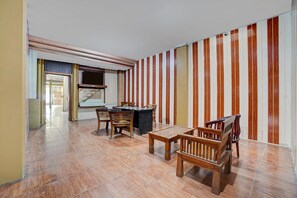 Una habitación con una mesa de comedor, sillas, un televisor y una pared a rayas.