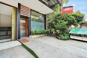 Un edificio comercial con escaparate que dice 'KOST' y un área de estar al aire libre techada.