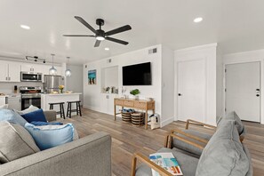 Ein modernes Wohnzimmer mit grauem Sofa, Couchtisch aus Holz und flachbildschirm-Fernseher an der Wand.
