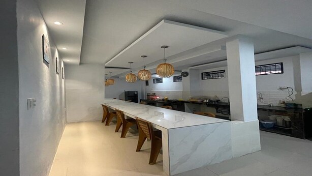 A modern kitchen with a marble island, pendant lights, and a long counter.