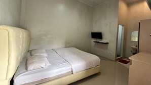 A room with a bed, a television, a mirror, and a sink.