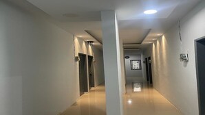 A hallway with a modern design, featuring a central column, recessed lighting, and a door at the end.