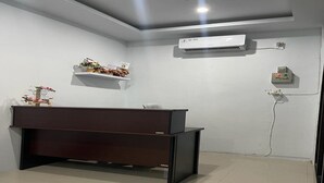 A reception desk, air conditioning unit, and a wall-mounted electrical outlet in a clean, modern room.