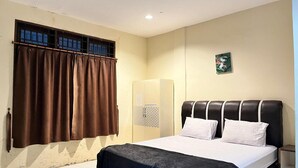 A bedroom with a bed, curtains, a wardrobe, and a small wall decoration. - Aljadid Pajus Deluxe Comfort (Medan)