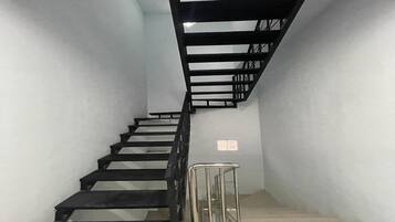 Eine Treppe mit Metallgeländer, weißen Wänden und einem kleinen Schild an der Wand.