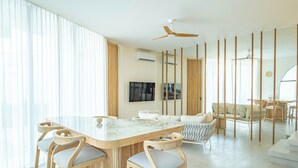 Una sala de estar moderna con una isla de mármol, sillas de madera, un sofá y un ventilador de techo.
