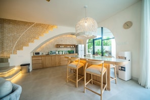 Une cuisine moderne avec un mur de protection en pierre, des meubles de rangement en bois et un grand îlot central doté de tabourets de bar.