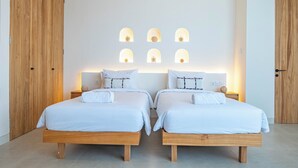 Un dormitorio moderno con dos camas, cabeceros de madera y una pared con nichos iluminados.