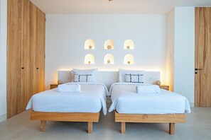 Un dormitorio moderno con dos camas, cabeceros de madera y una pared con nichos iluminados.