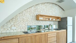 Una cocina moderna con pared de piedra, armarios de madera y estante empotrado.