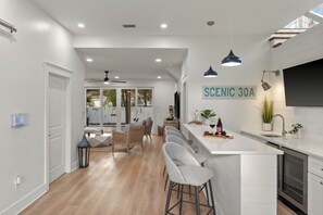 Una cocina moderna con barra, armarios blancos e iluminación colgante.