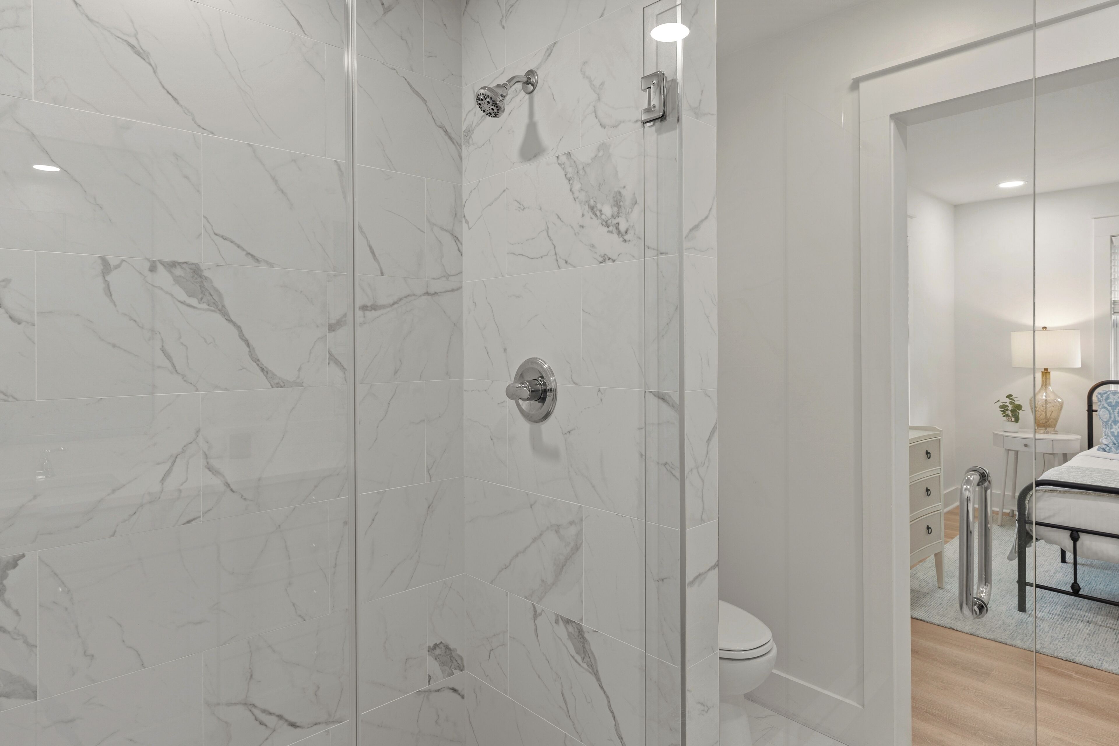 Ein modernes Badezimmer mit Duschkabine, Toilette und einem Bett mit Nachttisch.