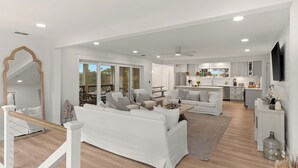 A spacious living area with a white sofa, a dining table, and a kitchen in the background. - Sleeps 18 + Pool + Hot Tub + Wet Bar | Walk to the Beach | The Salty Pearl (Santa Rosa Beach)