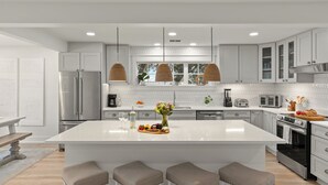 A modern kitchen with white cabinetry, a large island, pendant lights, and stainless steel appliances. - Sleeps 18 + Pool + Hot Tub + Wet Bar | Walk to the Beach | The Salty Pearl (Santa Rosa Beach)