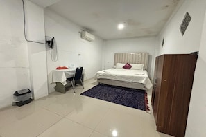 A small, clean room with a bed, a desk, a chair, and a wardrobe.