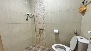 Ein Badezimmer mit Dusche, Toilette und einem gemusterten Boden.