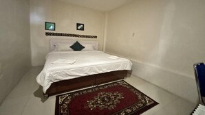 Ein Schlafzimmer mit einem Bett, einem roten Teppich mit Muster und zwei Bildern an der Wand.