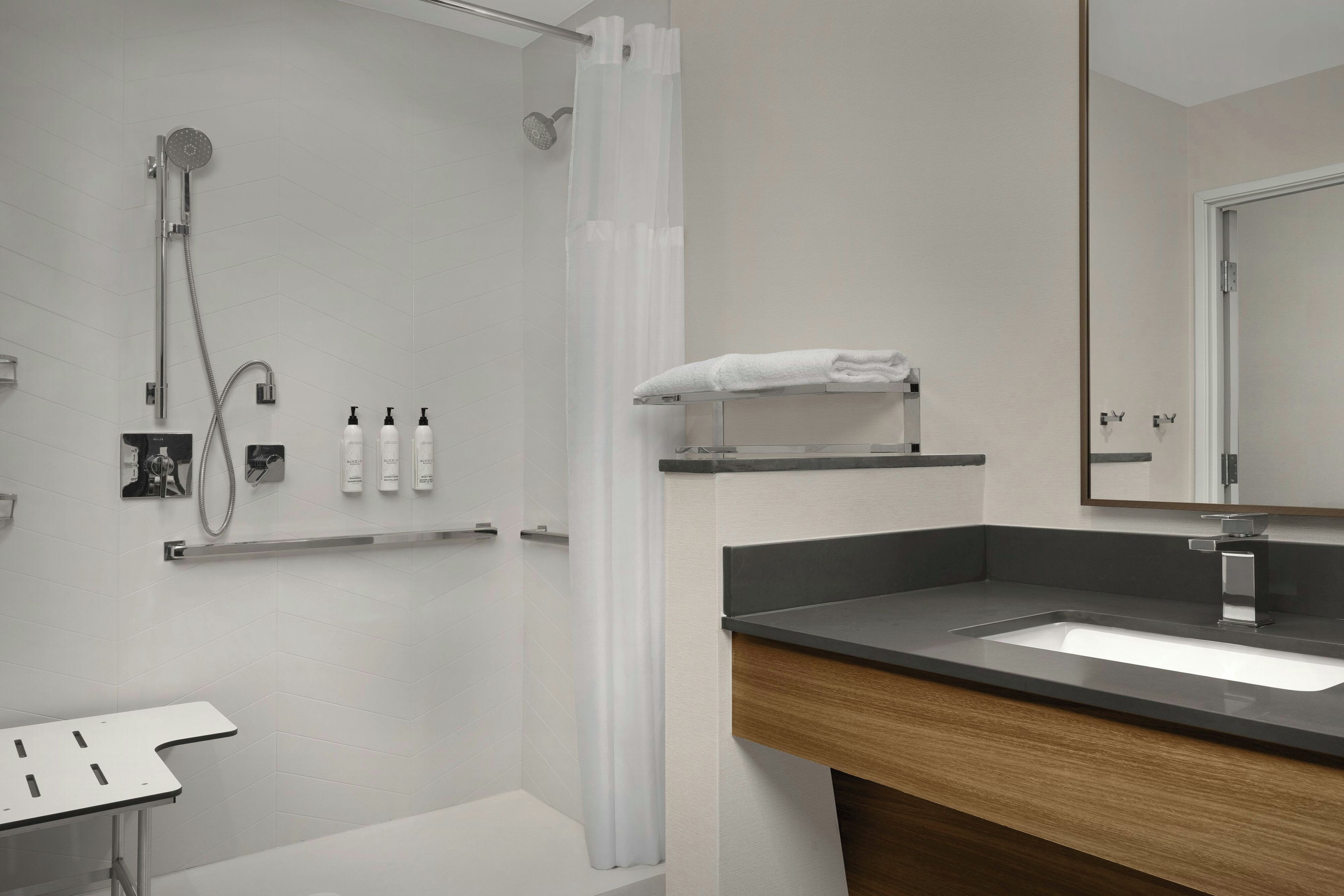 Ein modernes Badezimmer mit Dusche, Waschbecken und Spiegel.