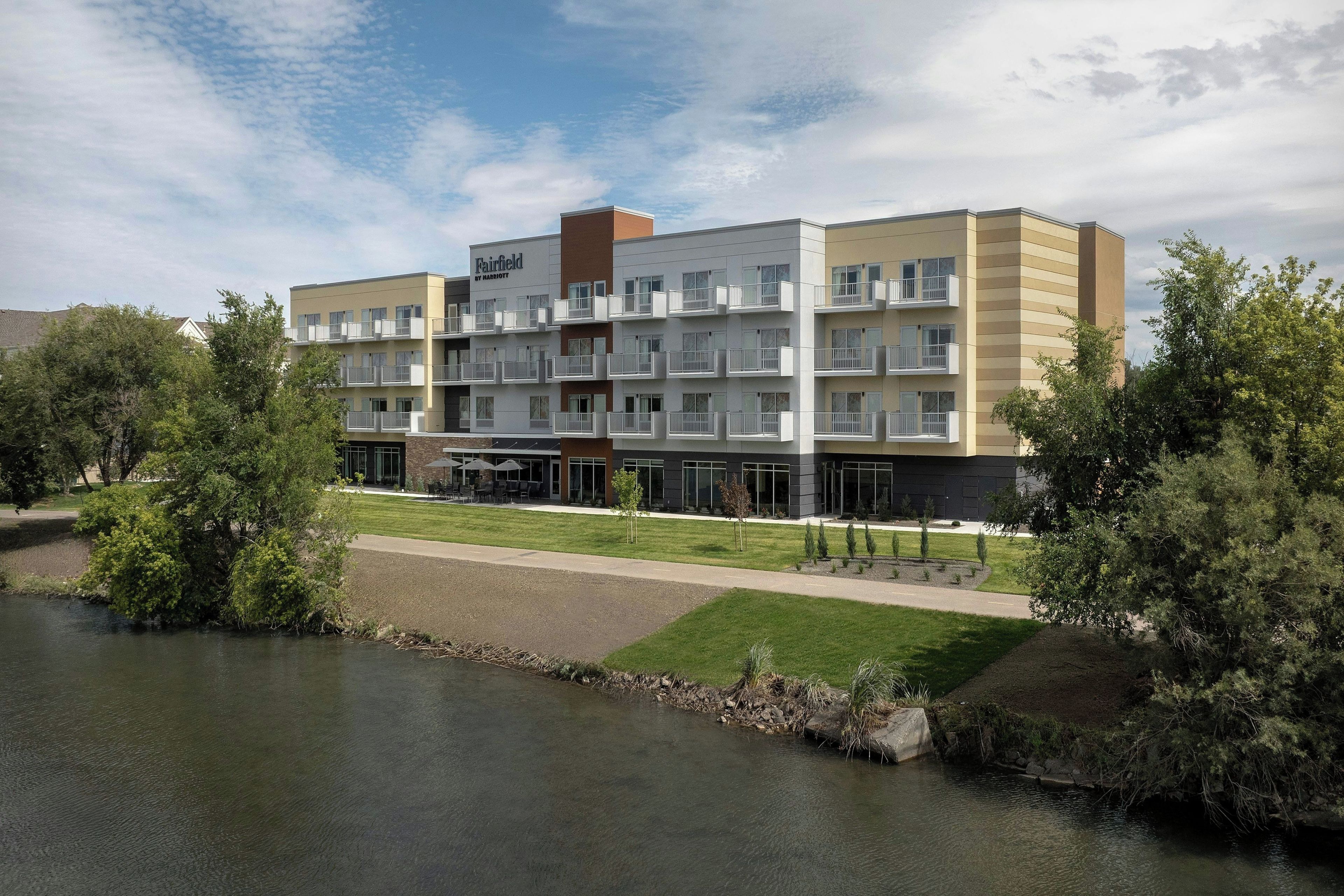 Ein mehrstöckiges Hotel mit flachem Dach, einem Schwimmbad und einer begrünten Anlage mit Bäumen.