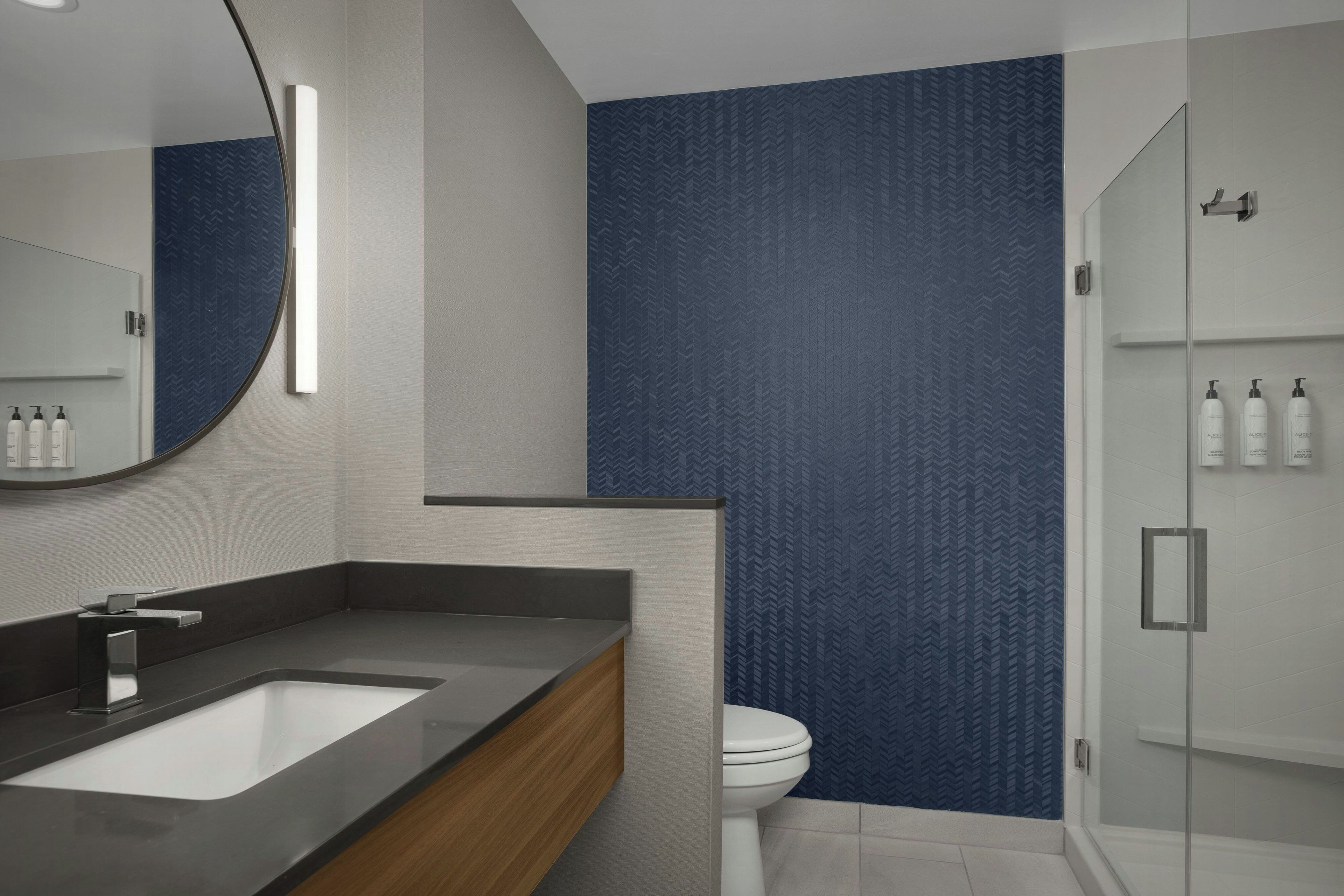 Un baño moderno con un espejo grande, un lavabo y un inodoro.