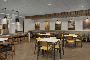 A restaurant interior with booths, tables, and hanging pendant lights.