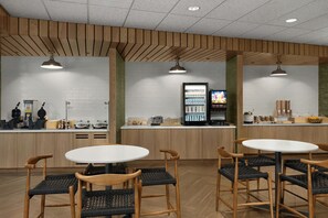 L'intérieur d'un café moderne se caractérise par des plafonds recouverts de lambris en bois, des murs en briques blanches et un comptoir central doté d'un distributeur de boissons.