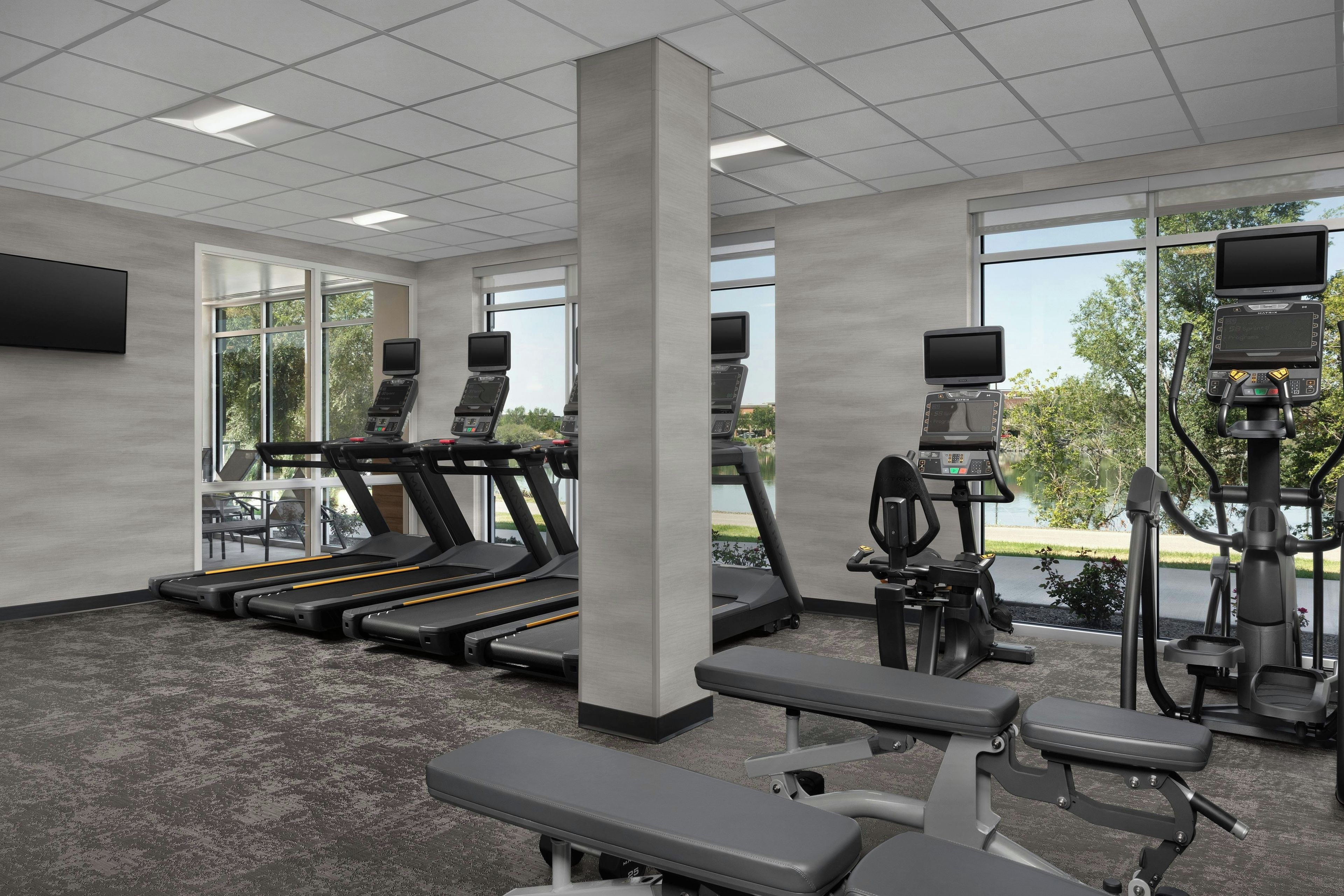 Une salle de sport équipée de tapis de course, de vélos d’exercice et d’un banc de musculation.