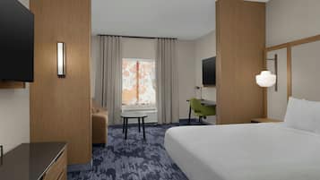 A hotel room with a bed, a desk, a chair, a television, and a window with curtains.