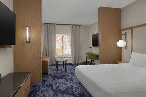 Une chambre d’hôtel équipée d’un lit, d’un bureau, d’une chaise, d’une télévision et d’une fenêtre avec des rideaux.