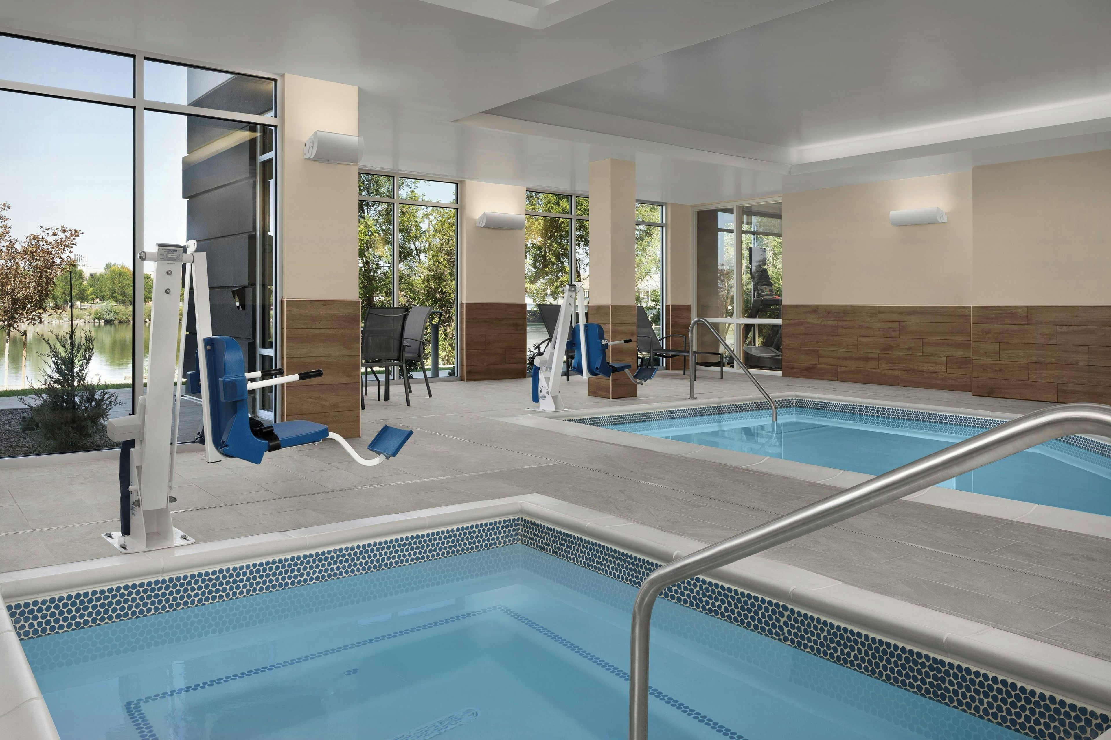 Zona de piscina de hotel con dos piscinas, equipo de ejercicio y sillas de descanso.