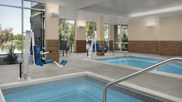 Zona de piscina de hotel con dos piscinas, equipo de ejercicio y sillas de descanso.