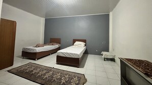 Quarto com duas camas, uma mesinha, televisão e um tapete estampado.