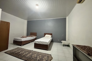 A room with two beds, a small table, a television, and a patterned rug.