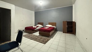 Quarto com duas camas, uma cadeira, um armário de madeira e piso ladrilhado.