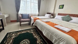 A hotel room with two beds, a desk, a chair, and a large window with curtains. - Poma Zainoel Deluxe Twin (Banda Aceh)