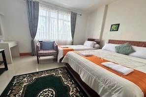 Hotellihuone, jossa on kaksi sänkyä, työpöytä, tuoli ja suuri ikkuna, jossa on verhot.