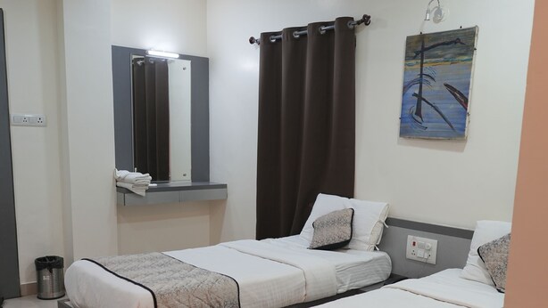Een hotelkamer met twee bedden, een plafondventilator, een schilderij en een kleine prullenbak.