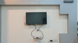 Een aan de muur bevestigde televisie met een plat scherm, aangesloten op een stekkerdoos met meerdere stopcontacten.