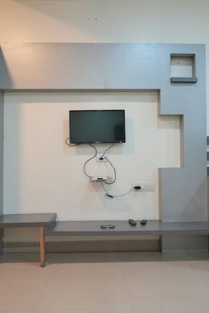 A wall-mounted television with a flat-screen display, connected to a power strip with multiple outlets.
