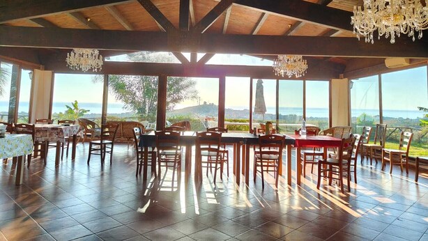 Un comedor al aire libre con vigas de madera, ventanas amplias y candelabros.
