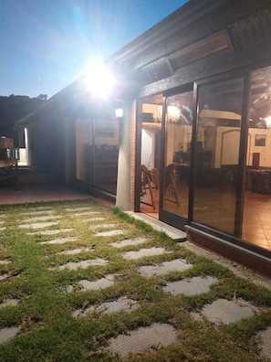 A building with large glass doors, a paved outdoor area with stepping stones, and a visible interior with furniture. - Cozy Gallelli Castle Farmhouse in Badolato (Calabria)