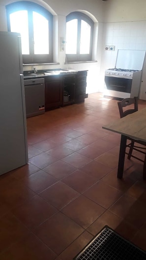 Eine Küche mit Kühlschrank, Herd und Fliesenboden.