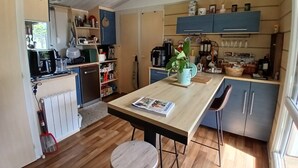 Une cuisine compacte avec un plancher en bois, un îlot central et un coin repas équipé d’une chaise.