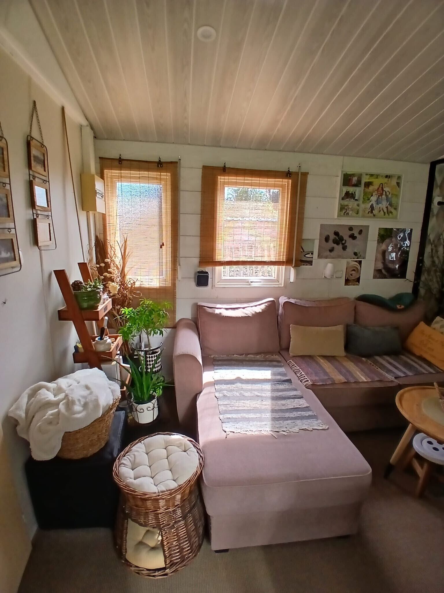 Una sala de estar acogedora con un sofá, una mesita, una cesta y una silla de mimbre.