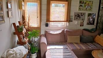 Una sala de estar acogedora con un sofá, una mesita, una cesta y una silla de mimbre.