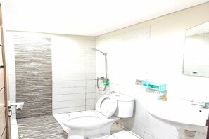 Une salle de bain équipée de toilettes, d’une douche et d’un lavabo.