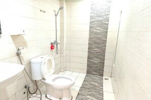 A small bathroom with a toilet, a sink, and a shower.