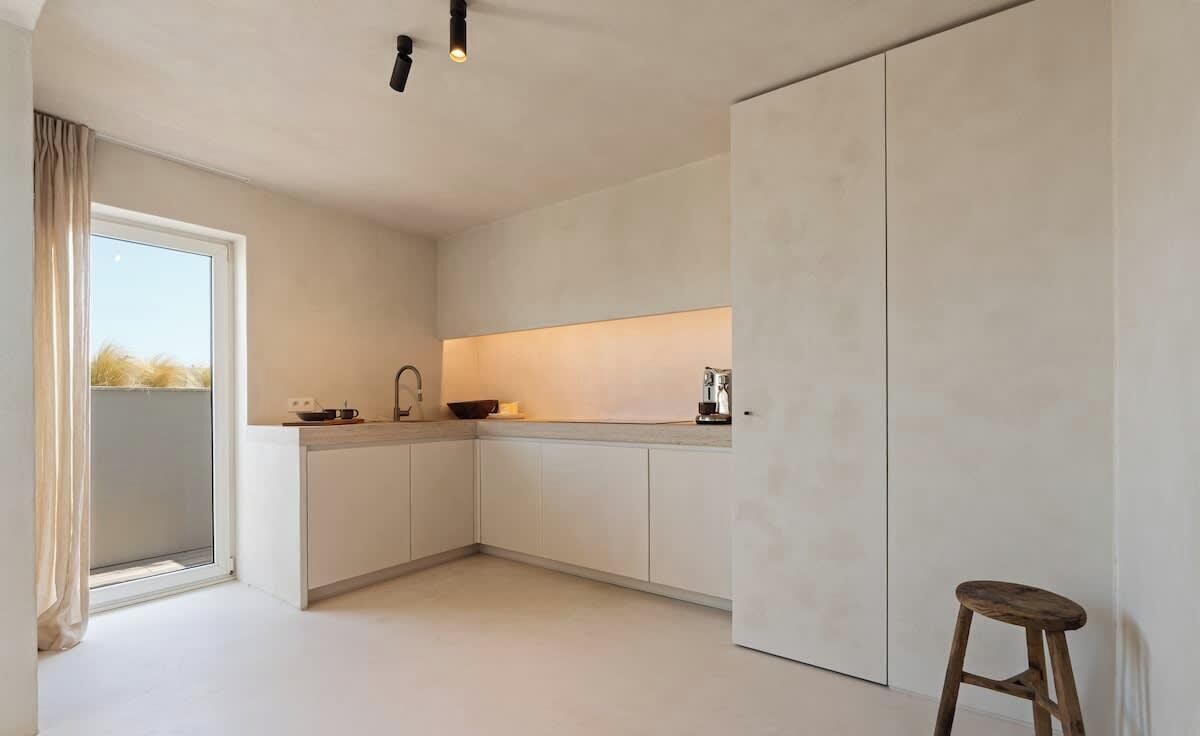 Una cocina moderna con armarios blancos, un lavabo y un taburete.