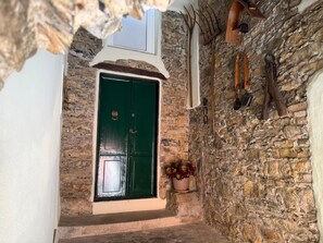 A stone wall with a green door, a window, and a potted plant. - Apartment 'Rosmarino' with Sea View, Wi-Fi, and Air Conditioning (Moglio)