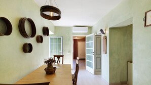 A dining area with a wooden table, chairs, a hanging light fixture, and a wall-mounted air conditioning unit. - Apartment 'Rosmarino' with Sea View, Wi-Fi, and Air Conditioning (Moglio)